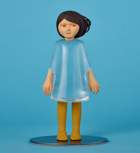 a small sculpture by Ayako Kita made of cypress and acrylic resin, depicting a young woman with a dress made of clear material so that we can see right through her