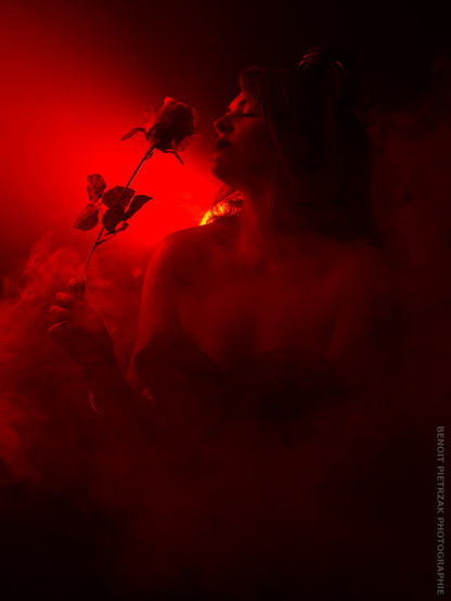 Studio photograph of a woman and a rose, with red lighting.
