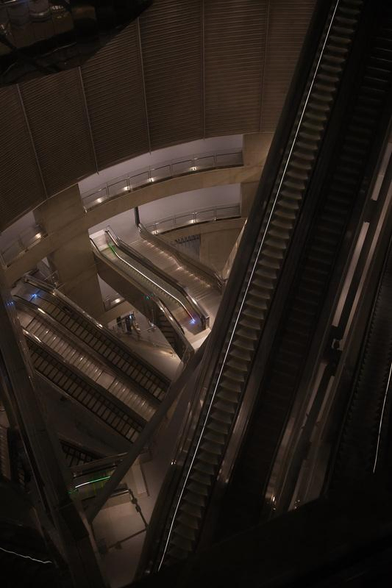 Photo en plongée d’escalators allant très bas dans un bâtiment plein de surfaces réfléchissantes en métal