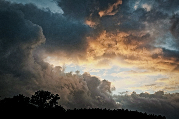 Dramatic sky with dark clouds an the sun lighting up under the clouds