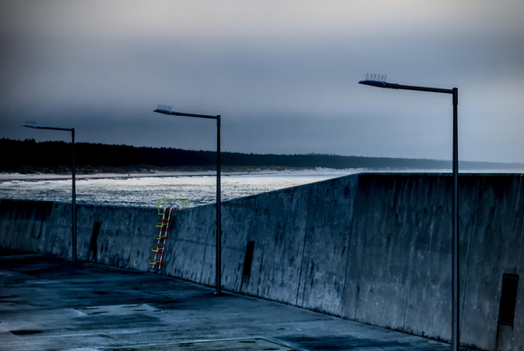 Color photo showing a pier at dusk, with a beach in the background, late fall/early winter, Baltic Sea.