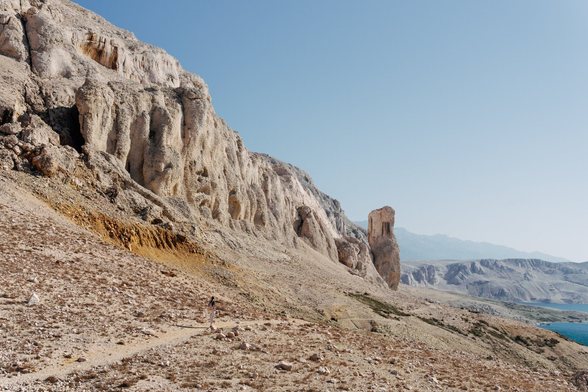 Bright mountains with blue sky, the landscape looks like it's from Mars. There is a path through mountains.