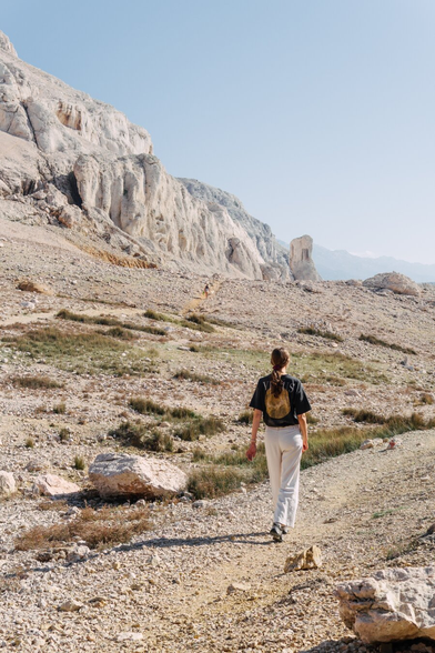 The bright mountains and blue sky make the landscape look like something from Mars. A path leads through the mountains, along which a woman is walking.