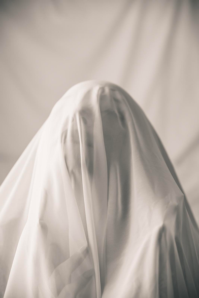 Mujer bajo tela blanca.