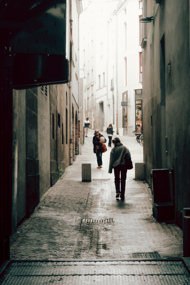 People walking in a ascending street, from the dark to the light