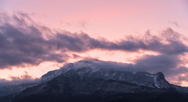 Photo d'un coucher de soleil sur le Vercors (côté Grenoble). il ya des bandes de nuages sombres sur l’image et autour du sommet du Moucherotte, mais dans l'ensemble le ciel est dégagé avec une belle teinte rose. Le haut de la montagne est couvert de neige tandis que le bas est plus sombre car il ne fait pas assez froid.