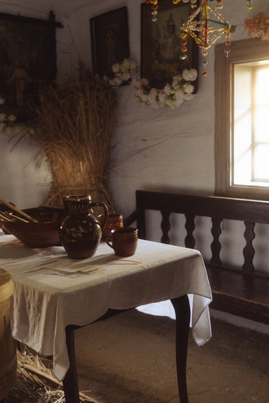 A table with a jug, bowls and cups. The light streaming through the window.