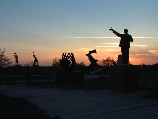Late afternoon sunset in shades of blue, pink & white over a park with Soviet statues that have been removed from public display, the most prominent of which is Vladimir Ilyich Ulyanov (Lenin.)