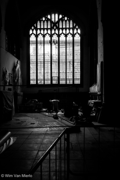 Black and white image of the church interior. Beyond temporary barriers in the foreground is large window.