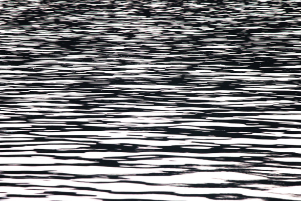 Photograph of white light reflected on the surface of a lake, forming a patterns of white and black shapes stretched horizontally on the ripples.