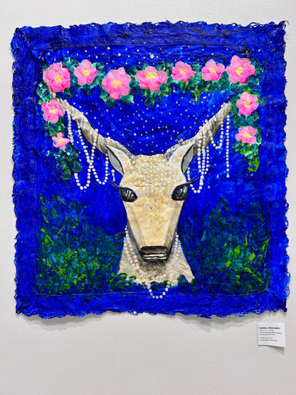 Маляўнічая карціна са стылізаванай галавой аленя з вялікімі рагамі, упрыгожанымі кветкамі і жэмчугам. Фон ярка-блакітны, дапоўнены зялёнай лістотай і ружовымі кветкамі. Мастацкая работа мае мудрагелісты, дэкаратыўны характар.