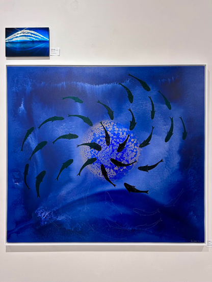 Абстрактны твор мастацтва з цёмна-сінім фонам і закручанымі ўзорамі. Цёмныя сілуэты рыб размешчаны па крузе, акружаючы яркае, тэкстураванае сіняе кола, якое нагадвае бурбалкі або святло.