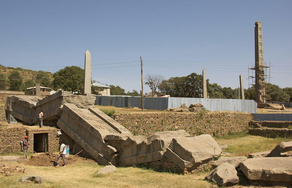 a photograph of several men working around a giant broken bridge like stone structure, it was standing, steleas are funerary markers I believe and they were really impressive in this part of the world