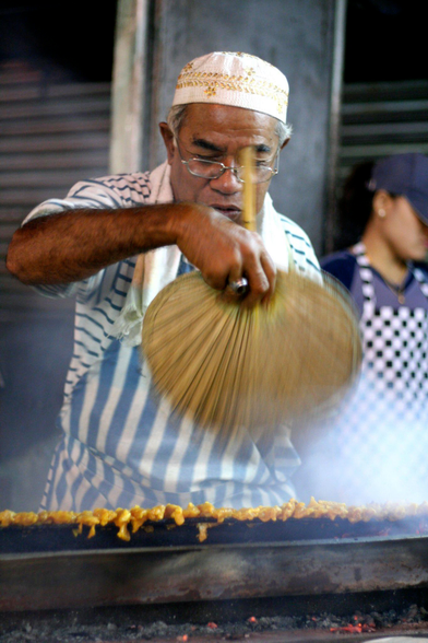 photo of a Malay man fanning satay (meat on skewers) on the streets of malaysia