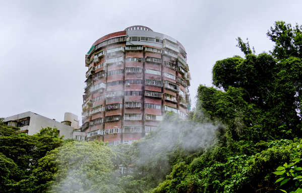 A spherical residential building behind trees, slightly obscured by hot steam from thermal springs in the foreground.