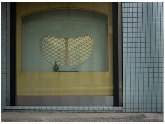 A window I love, in a building near Satake Yokocho in Tokyo. Blue tiles, a wood and shoji screen behind a curved aperture of blue painted wood, of the same shade of blue as the tiles outside. A single ceramic vase and two miniatures of shrine lanterns are on display inside. 