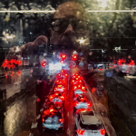 A view of nighttime traffic, blurred through a rain-soaked window, showcasing red and white car lights.