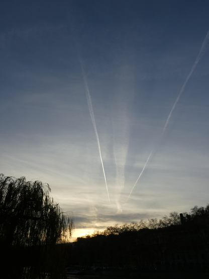 Picture of the sunset, with some contrails left by planes seeming to emanate from behind the hills.