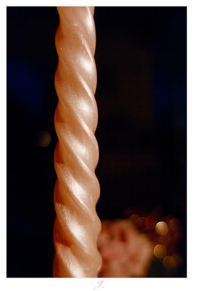Close-up of a salmon colored candle, the surface of which is illuminated from the right by another candle which we cannot see. The body of the candle has a screw-like structure and the "thread-line" goes up, meandering diagonally from bottom right to the top left. The background is almost black, at the bottom some blurred orange and red spots can be seen.

AI disclaimer: Using my work, its meta data, written or derived description to create media with or train AI based systems is prohibited.