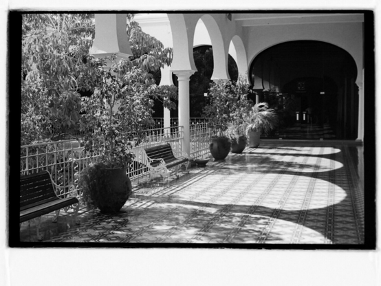 Black and white photo of sunlit terrace with colonnade