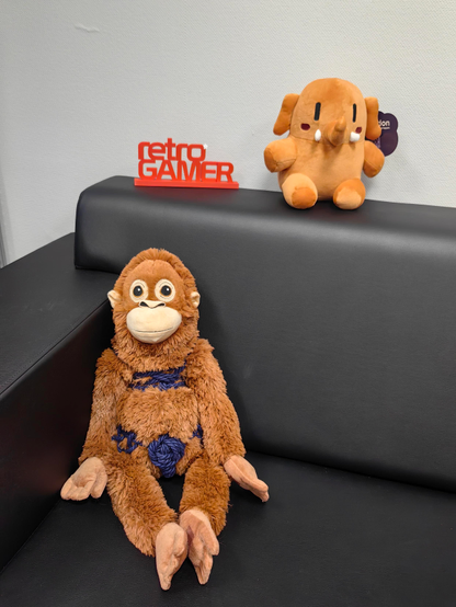 Bild einer schwarzen Couch mit einem Bondageäffchen, einen Retro Gamer 3D Druck und dem Plushtodon im Orange.