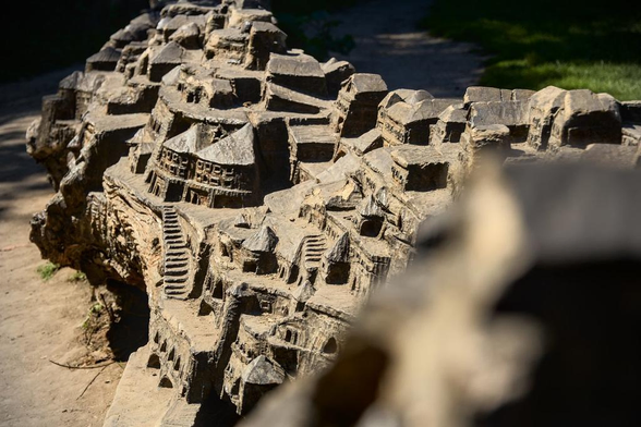 photo de très près d’une sculpture en bois représentant une cité sur plusieurs étages, avec des escaliers et plein de petites maisons