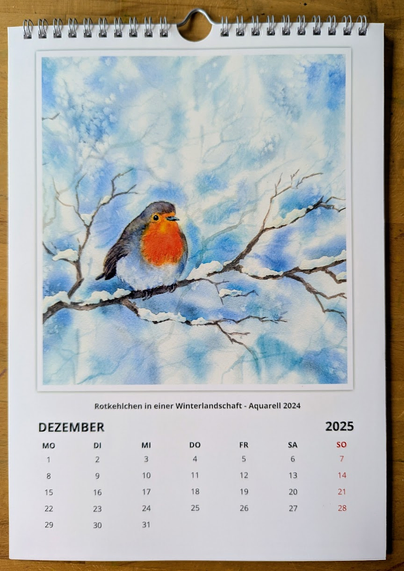 December calendar page featuring my painting Robin in a winter landscape - a watercolor painting in landscape format hand-painted by the artist Karen Kaspar.
A European Robin sits on a snow-covered branch in the middle of a gentle winter scene. The bright orange breast feathers form a striking contrast to the soft, cool colours of the wintry background. Delicate twigs are lightly dusted with snow, lending the scene a calm and frosty atmosphere. Soft blue and white tones fill the background and suggest a cold but calm atmosphere.
