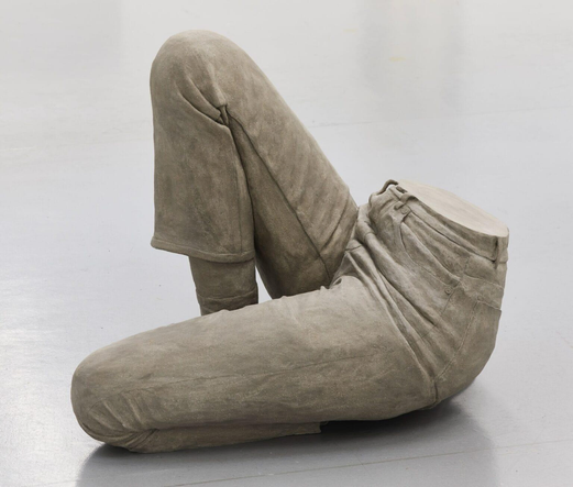 a ceramic sculpture by Léonore Chastagner of a woman's lower half, clothed in jeans, seated with one knee in the air
