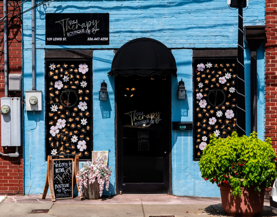 A color photo of a light blue painted facade on a shop called "Retail Therapy Boutique".