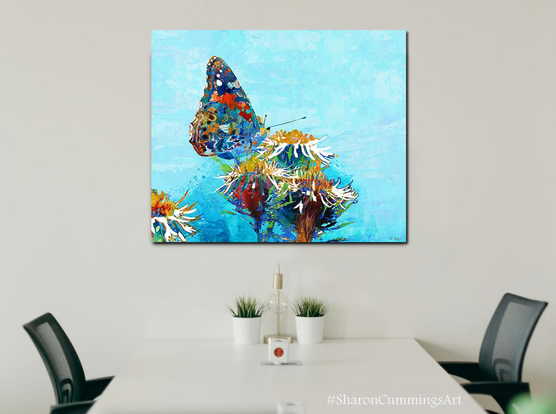 Colorful butterfly and thistle flowers on blue watercolor by artist Sharon Cummings.