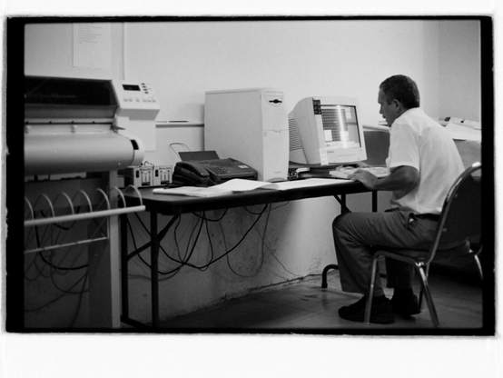 Black and white photo of man working at computer