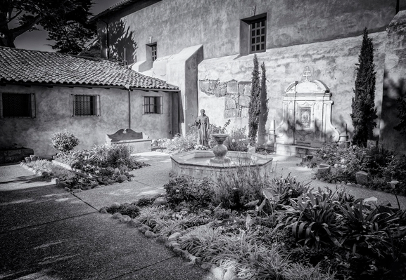 Courtyard of Carmel Mission with fountain and statue of Junipero Serra.