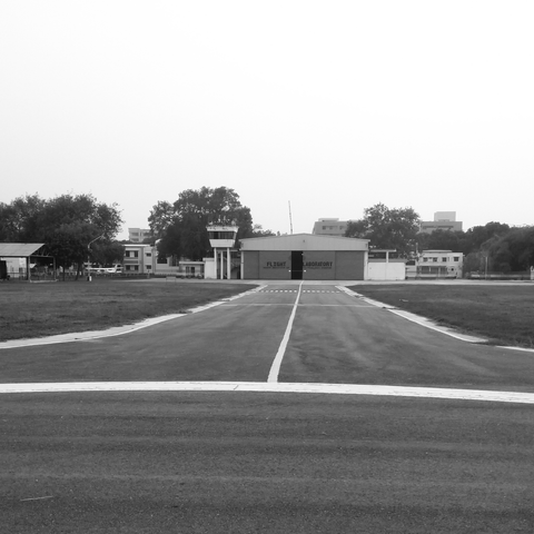 A black-and-white photo of an empty runway leading to a hangar labeled "Flight Laboratory." Surrounding trees and structures suggest a calm, overcast day.