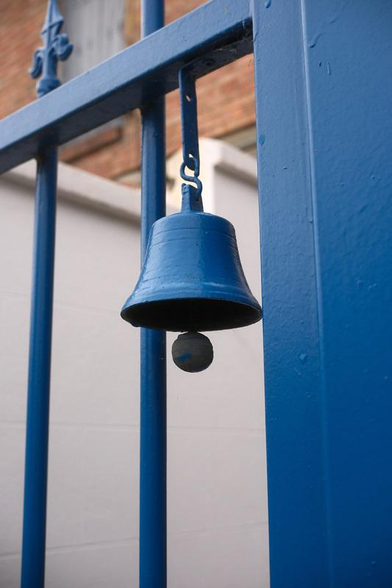 Photo d’un Gros plan sur une clochette accrochée à une grille, le tout de couleur bleu Tardis  