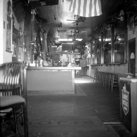 A black-and-white film photo. An old bar sits eerily empty and closed the day before Thanksgiving in downtown Austin, Texas. Wednesday, November 26, 2025.