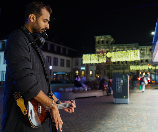 Ukulele-playing street musician in front of the Porta Nigra in Trier at night