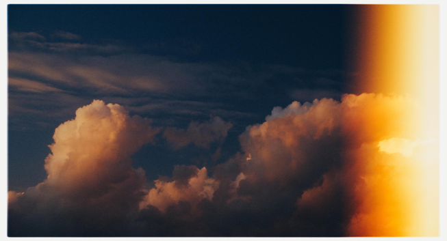 Dramatic clouds lit by golden sunlight with light leaking.