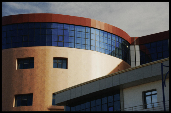 Modern building with curved red roof and glass facade.
