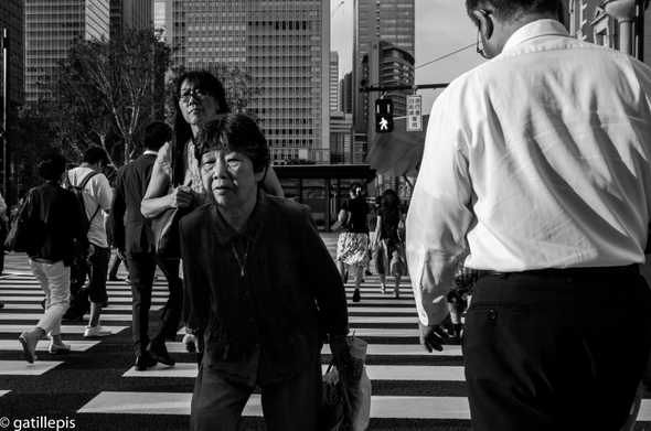 Dona gran, una mica geperuda, mentre travessa un pas de vianants.