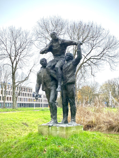 Two athletes standing, holding third athlete on their sholders, in pose expressing pride in their accomplishments