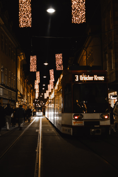 photo of a tram driving through the city by night.