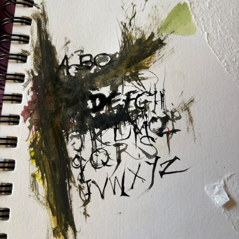 A mixed media artwork featuring letters of the alphabet in a stylized, abstract form. The background has splashes of colors like green, yellow, and deep brown, with a spiral binding visible on the left side.
