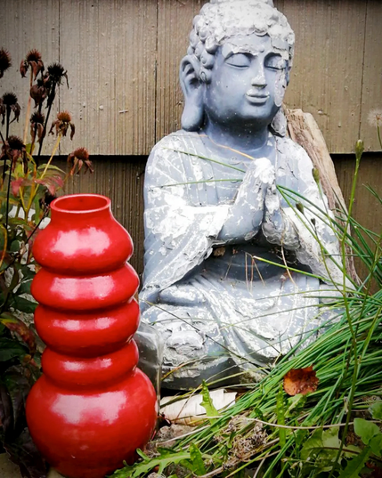 Red raku vase with Buddha outside.