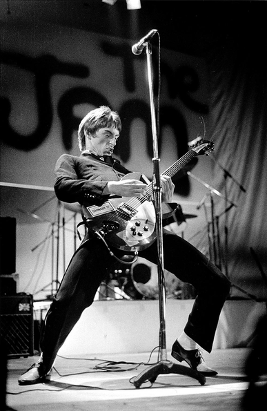 Paul Weller performing onstage with Rickenbacker guitar. 
