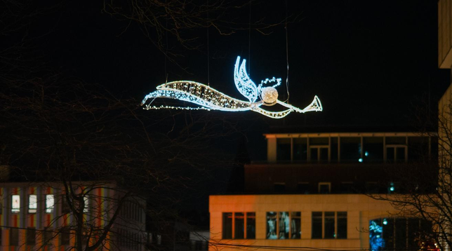 Ein Engel aus warmen und kalten weißen LEDs schwebt über den Fassaden von Häusern, die an den Weihnachtsmarkt angrenzen