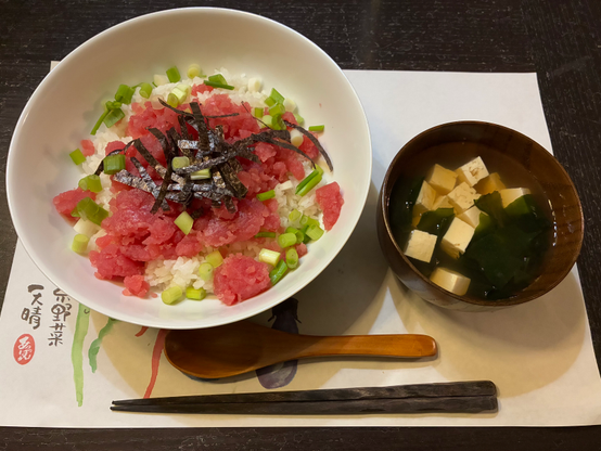 Fresh red raw tuna on the rice sprinkled with green onions and a tofu soup on the side.
