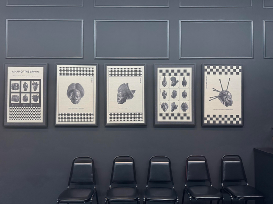 art installation by Tavares Strachan. prints of stylized afros and braids in a monochromatic black barber shop 