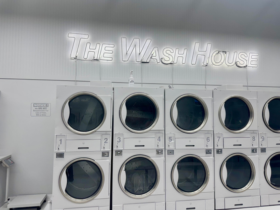 art installation by Tavares Strachan. a monochromatic grey laundry mat with neon sign reading the THE WASH HOUSE
