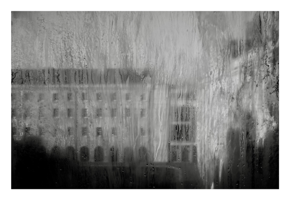 An abstract black and white shot of a museum taken through a dirty window, creating a painting like effect. 