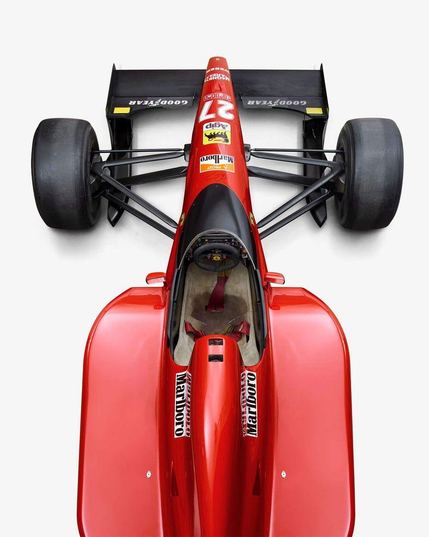 Top view of a classic red Ferrari Formula 1 race car with large tires, featuring sponsor logos, a streamlined body, and an open cockpit.